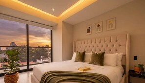 Ein modernes Schlafzimmer mit großem Fenster, einem gepolsterten Kopfteil und Blick auf die Stadt.