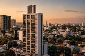 A high-rise building with multiple floors and balconies, surrounded by a dense urban environment with various other buildings.