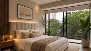 Un dormitorio moderno con una cama grande, una mesita de noche con lámpara, un cuadro enmarcado en la pared y vistas a zonas verdes a través de la ventana.