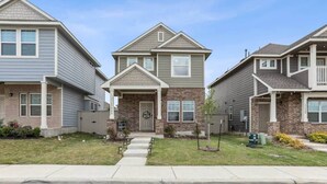 A row of townhouses with a central entrance, brick facade, and a small front yard with a pathway leading to the door. - Lakeside Paradise - Pflugerville (Pflugerville)