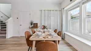 A dining area with a table set for four, a staircase, a door, and a window with curtains. - Lakeside Paradise - Pflugerville (Pflugerville)