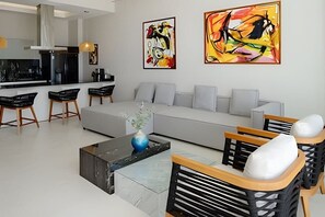 A modern living room with a sofa, coffee table, and chairs. There are abstract paintings on the wall. - Coastal condo w/ pool, bikes & beach access (Corral del Risco)