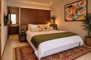 Ein Schlafzimmer mit einem Bett, Nachttischen, einem Wandfernseher, einem Gemälde und einer Topfpflanze.