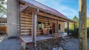 Een vakantiehuis in blokhutstijl met een overdekte veranda, houten banken en een pad van stenen dat naar de ingang leidt.