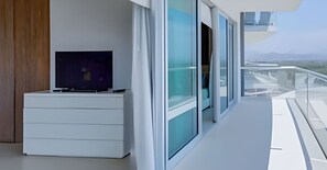 Relax in a spacious living area with a flat-screen TV and sliding glass door leading to a balcony with a view.