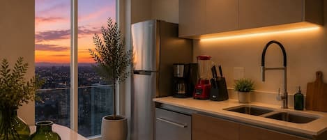 A modern kitchen with a stainless steel refrigerator, a coffee maker, and a sink. There is a view of a cityscape through a large window.