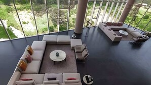 En moderne stue med en modulsofa, et sofabord og udsigt til en frodig have gennem store vinduer.