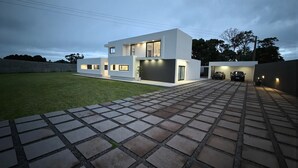 Uma casa moderna de dois andares, com entrada pavimentada e garagem.