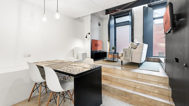 Un comedor moderno con una mesa, sillas y una zona de cocina al fondo.