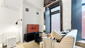 Una sala de estar moderna con un televisor de pantalla plana, un sofá, una mesa de centro y un radiador.