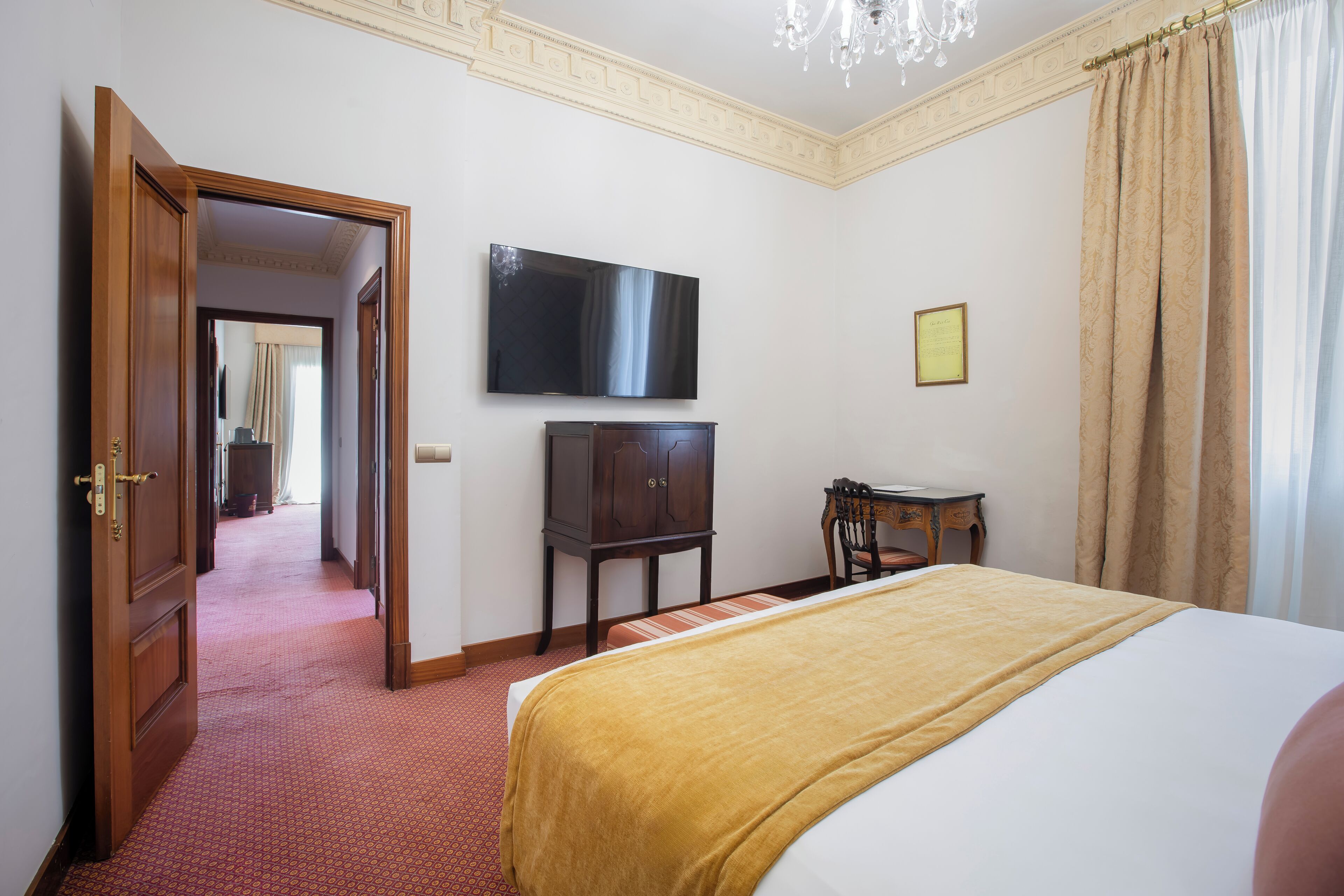 A hotel room with a bed, a television, a wardrobe, and a desk.