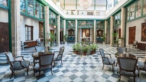 A spacious lobby with a checkered floor, multiple seating areas, and a central plant arrangement.