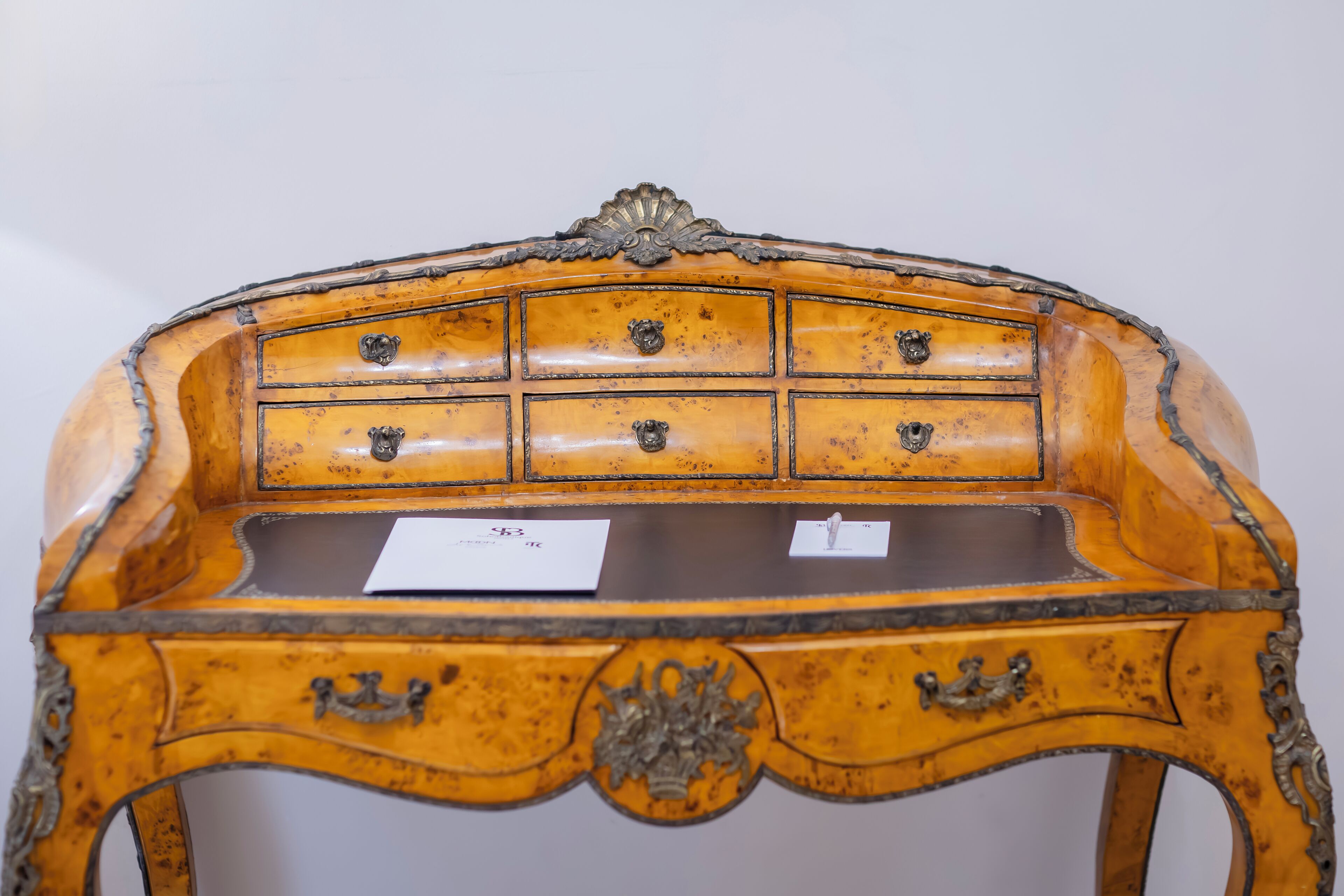 Ein antiker Holztisch mit zahlreichen Schubladen und verzierten Metallgriffen.
