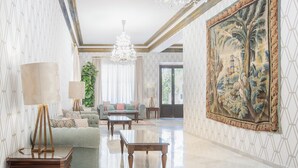 A spacious living room with a large painting, a chandelier, and a sofa set.