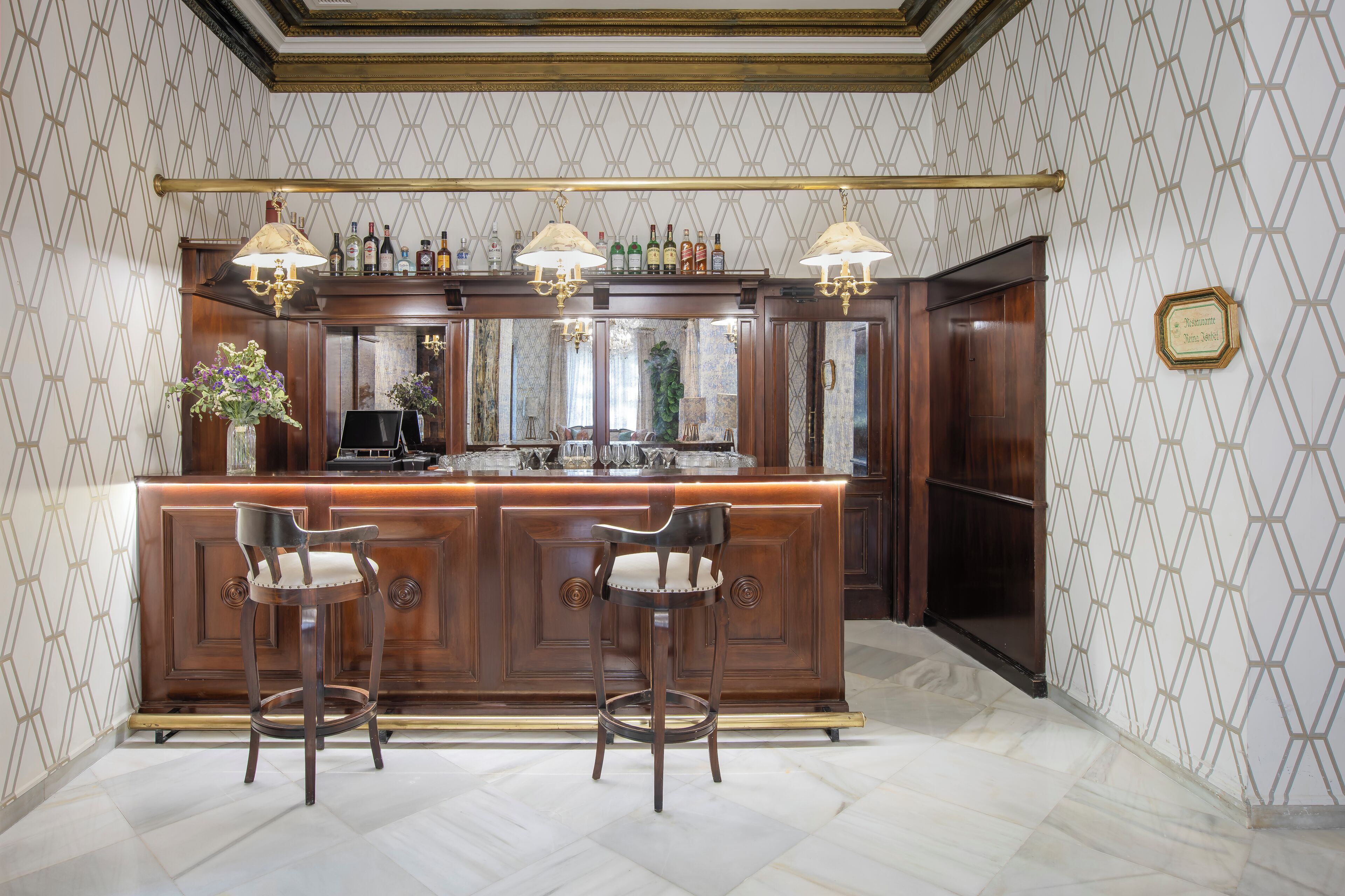 A bar area with a wooden counter, two bar stools, and overhead lighting.