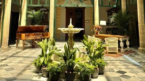 A spacious atrium with a checkered floor, a central fountain, and potted plants.