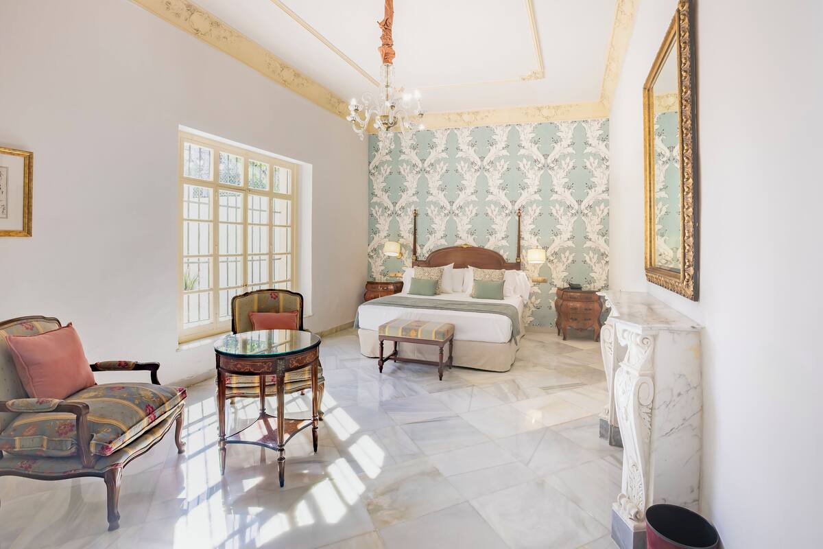 Une chambre à coucher avec un lit, une table en verre, une chaise, un canapé et une cheminée.