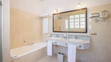 Un baño moderno con dos lavamanos, un espejo grande, una bañera y una ducha.