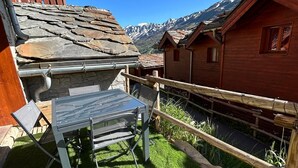 A patio with a table and chairs, a wooden fence, and a mountain view. - GREEN THISTLE (Valmeinier)