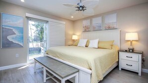 A bedroom with a bed, bedside tables, a bench, and artwork on the walls. - Relax in Peaceful Paradise at Sanibel Arms West Unit A1 -close to the Beach (Sanibel)