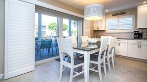 A modern kitchen with white cabinetry, a glass dining table, and a pendant light. - Relax in Peaceful Paradise at Sanibel Arms West Unit A1 -close to the Beach (Sanibel)