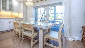 A modern kitchen with white cabinets, a glass dining table, and a chandelier. - Sanibel Arms West Newly Renovated Unit A2 First Floor Garden View (Sanibel)