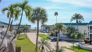 A resort with multiple buildings, palm trees, and a paved driveway. - Lush 2BR/2BA Sanibel Arms West Garden Unit A4 | Peaceful Oasis Near the Gulf (Sanibel)