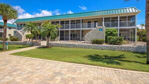 A hotel with a green roof, multiple balconies, and a stone facade. - Vibrant Unit B7 · Partial Gulf View | Just a 2 Minute Walk to the Beach (Sanibel)