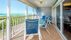 Ein Balkon mit Tisch und Stühlen, großen Fenstern und einem Deckenventilator.