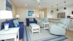 A modern living room with a sofa, armchairs, a coffee table, and a dining area with a kitchen in the background. - Breezy Unit D4 · Sanibel Arms West | Gulffront Breathtaking Gulf Views (Sanibel)