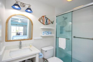 A bathroom with a large mirror, a sink, a toilet, and a glass shower enclosure.