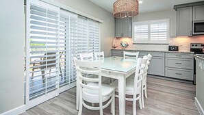 A modern kitchen with grey cabinets, a glass dining table, and white chairs. - Mesmerizing Unit E1 · Sanibel Arms West | Gulffront Magnificent Gulf Views (Sanibel)