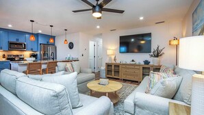 A modern living room with a sofa set, a coffee table, and a TV mounted on the wall.