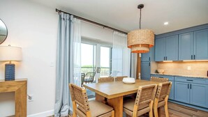 A modern kitchen with blue cabinets, a wooden dining table, and wicker chairs.