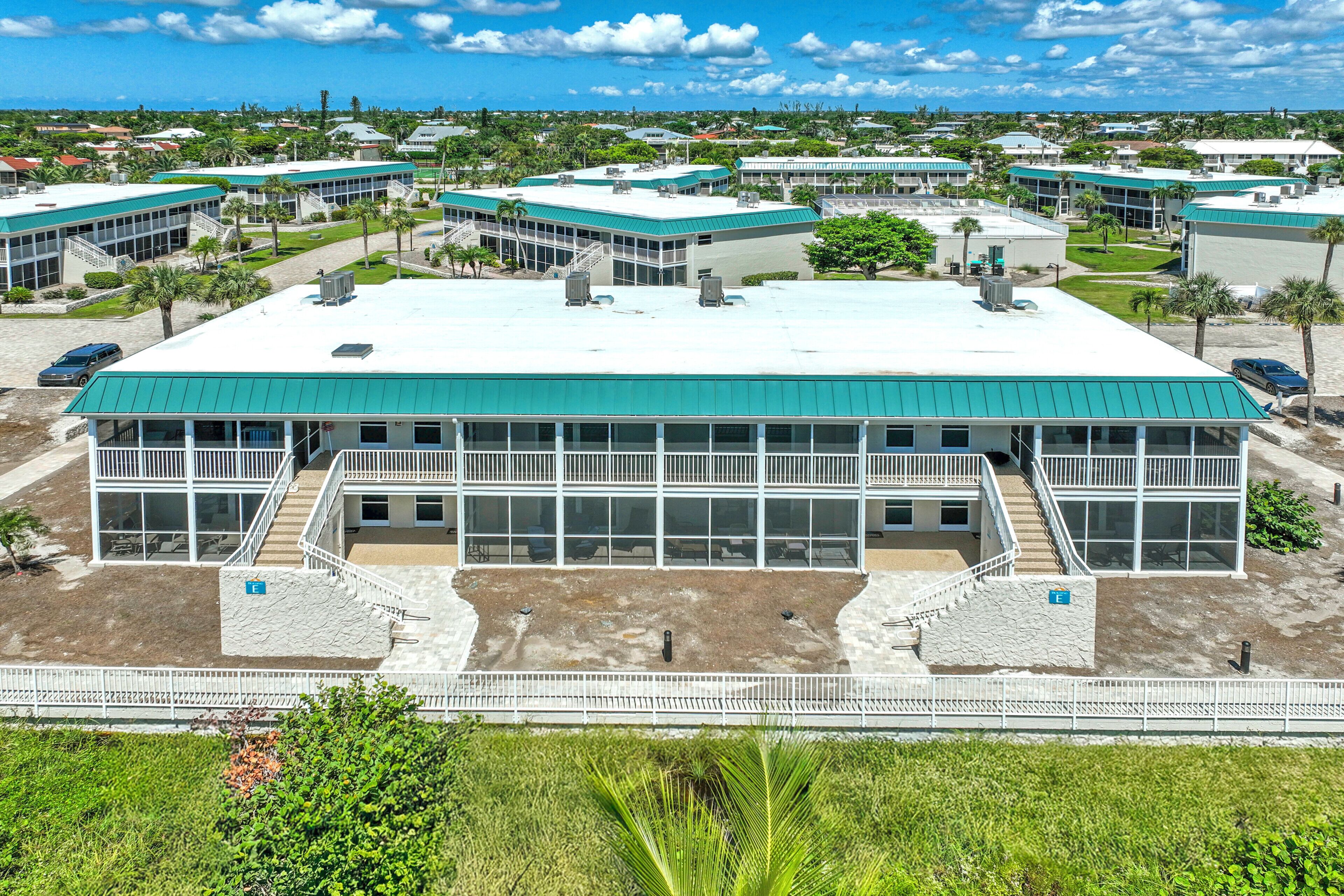 A modern building with a flat roof, multiple windows, and a central staircase.
