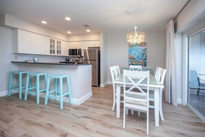 A modern kitchen with white cabinets, a stainless steel refrigerator, and a central island with bar stools. - Sanibel Beachfront Retreat/ Gulf Views/ Pool & Pickleball/ Bright & Updated (Sanibel)