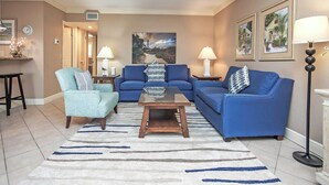 Un salon avec deux canapés bleus, un fauteuil bleu clair, une table basse et un tapis à motifs.