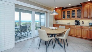 Une cuisine avec des meubles en bois, une table à manger avec des chaises et, par une porte-fenêtre coulissante, une vue sur un balcon.