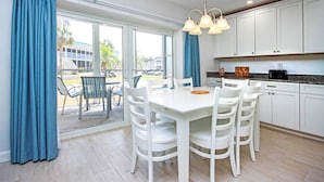 Una cocina moderna con armarios blancos, una mesa de comedor con sillas y vistas al exterior.