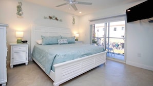 A bedroom with a bed, a nightstand, a ceiling fan, and a view of bicycles outside.