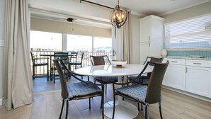 A dining area with a round table, four chairs, a chandelier, and a view of the outdoors. - Sanibel Vacation Rental | 2-Min Walk to Beach | Sanibel Arms West Condo (Sanibel)