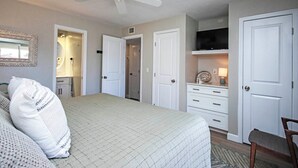 A bedroom with a bed, a ceiling fan, a dresser, a TV, and a door. - Sanibel Vacation Rental | 2-Min Walk to Beach | Sanibel Arms West Condo (Sanibel)