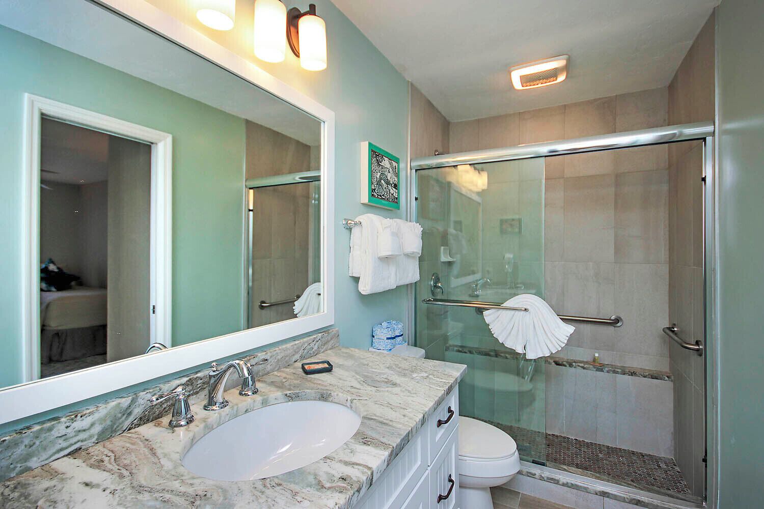 Une salle de bain avec un lavabo en marbre, une douche en verre et un grand miroir.