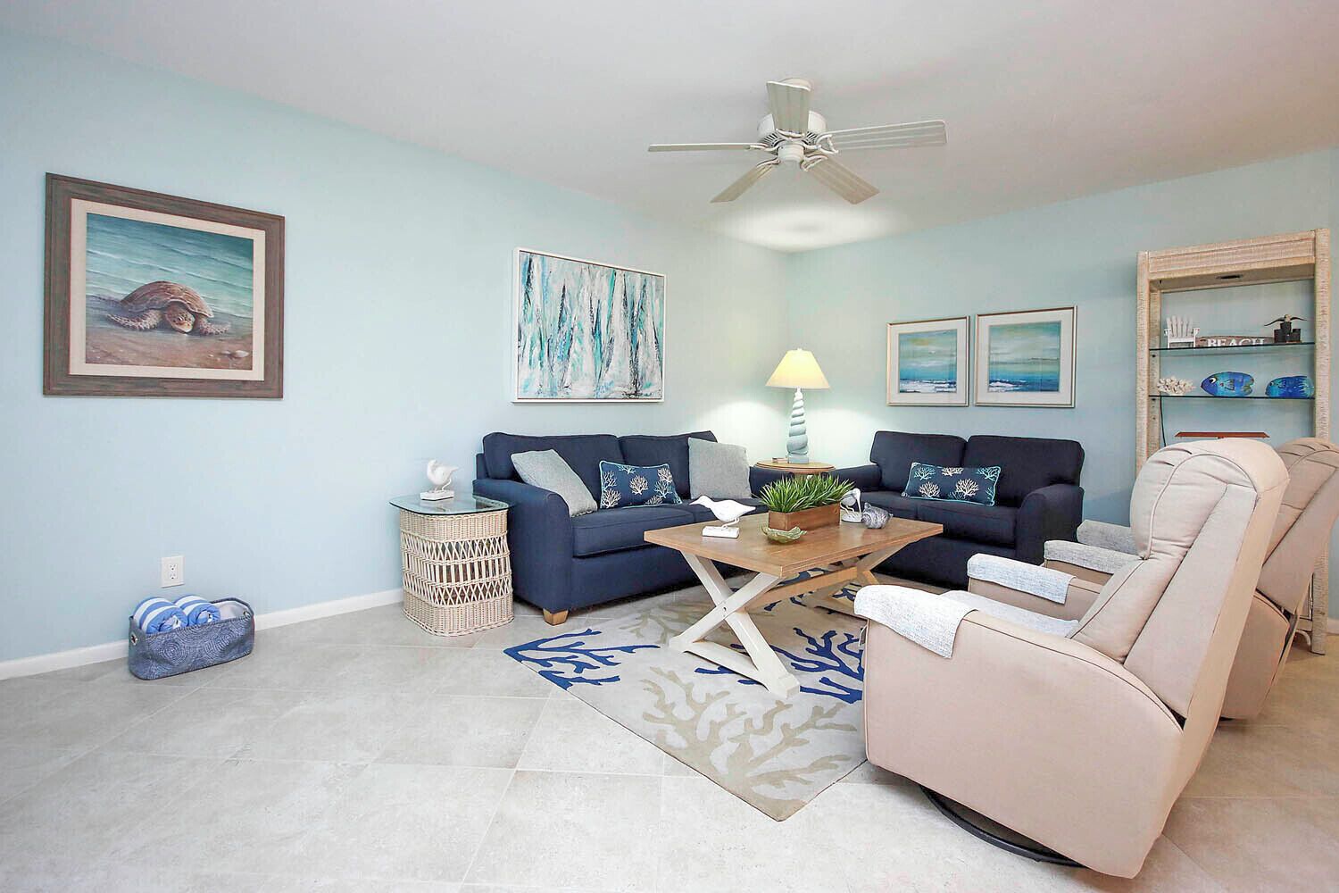 A living room with two sofas, a coffee table, a ceiling fan, and a small side table.