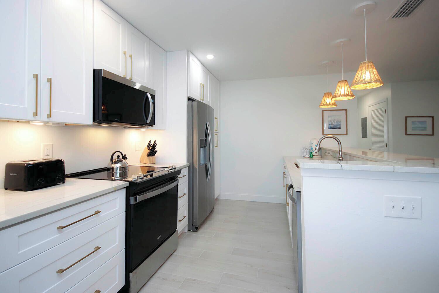 A modern kitchen with white cabinetry, stainless steel appliances, and pendant lighting.