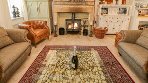 Una sala de estar acogedora con chimenea de piedra, sillones de cuero y un tapiz con leña.