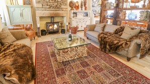 Una sala de estar acogedora con chimenea de piedra, vigas de madera y diversos objetos decorativos.