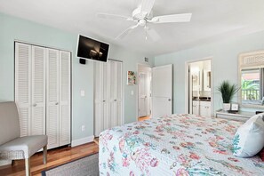 A bedroom with a bed, a chair, a ceiling fan, and a television. - Glimpse the Gulf While Relaxing on H8’s Screened Lanai (Sanibel)