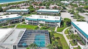 A resort with multiple buildings, a swimming pool, and a beach view.