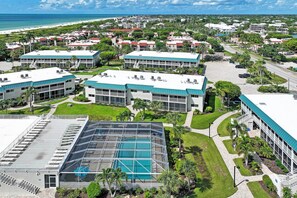 A resort with multiple buildings, a swimming pool, and a beach view.
